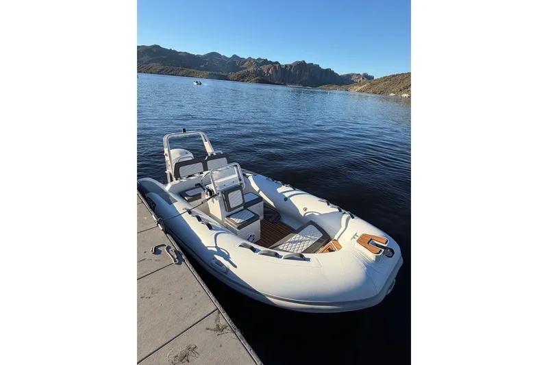Slide: The Image of 2027 Tide Craft Coronado 14 boat docked on a serene lake with mountainous backdrop. - 4