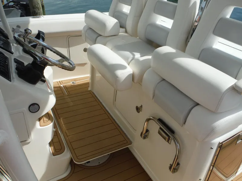 Slide: The Image of Das Bild zeigt den Steuerstand eines Boston Whaler 370 Outrage mit weißen Sitzen und Holzboden. - 45