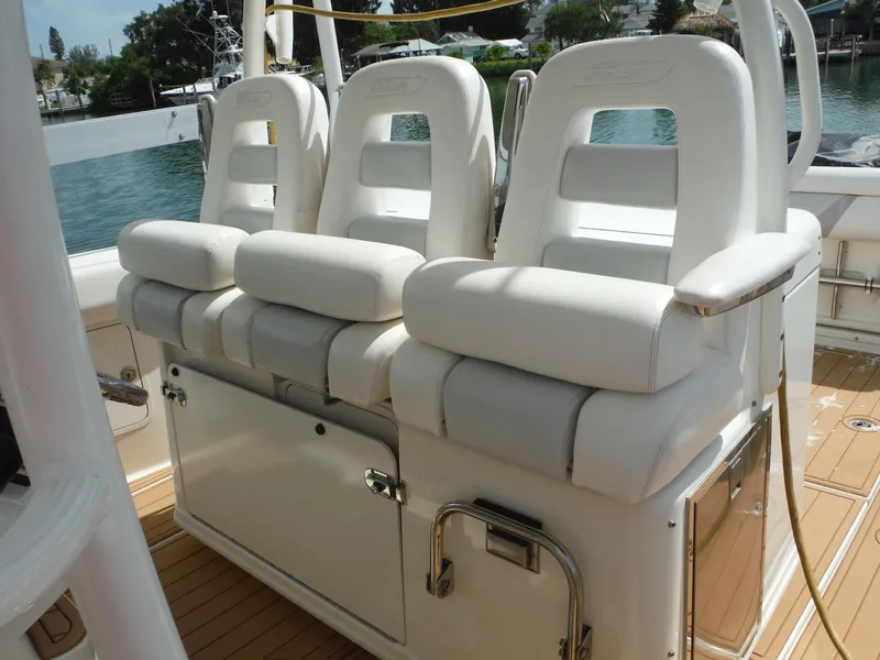 Slide: The Image of Drei gepolsterte weiße Sitze auf einem Boot mit Holzdeck, vor einer Wasserlandschaft. - 20