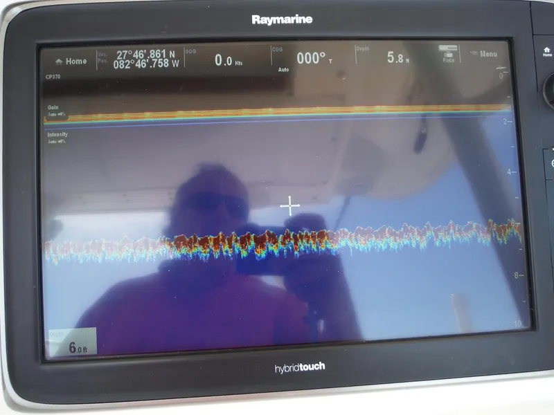 Slide: The Image of Ein Raymarine-Navigationssystem zeigt Tiefen- und Standortdaten an, reflektiert eine Person auf dem Bildschirm. - 40