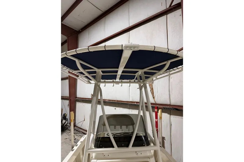 Slide: The Image of 1982 Shamrock 200 Open boat with blue canopy in a warehouse setting. - 20