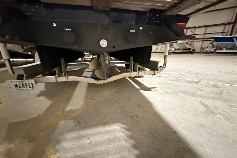 Slide: The Image of 1982 Shamrock 200 Open boat on trailer, showing propeller and hull in storage facility. - 16