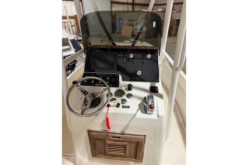 Slide: The Image of 1982 Shamrock 200 Open boat dashboard with steering wheel and controls in a warehouse. - 19
