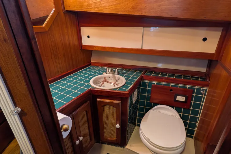 Slide: The Image of 1981 Custom 43 Pilothouse Trawler bathroom with green tiled countertop and wooden cabinetry. - 50