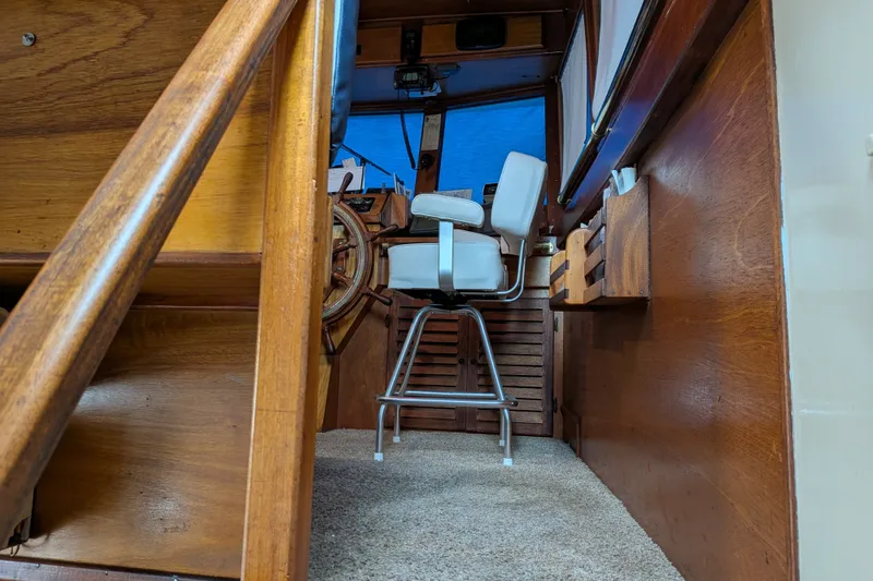 Slide: The Image of Interior of 1981 Custom 43 Pilothouse Trawler with wooden helm and white captain's chair. - 54