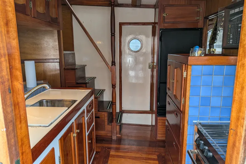 Slide: The Image of Interior of 1981 Custom 43 Pilothouse Trawler with wooden cabinetry and blue-tiled kitchen. - 24