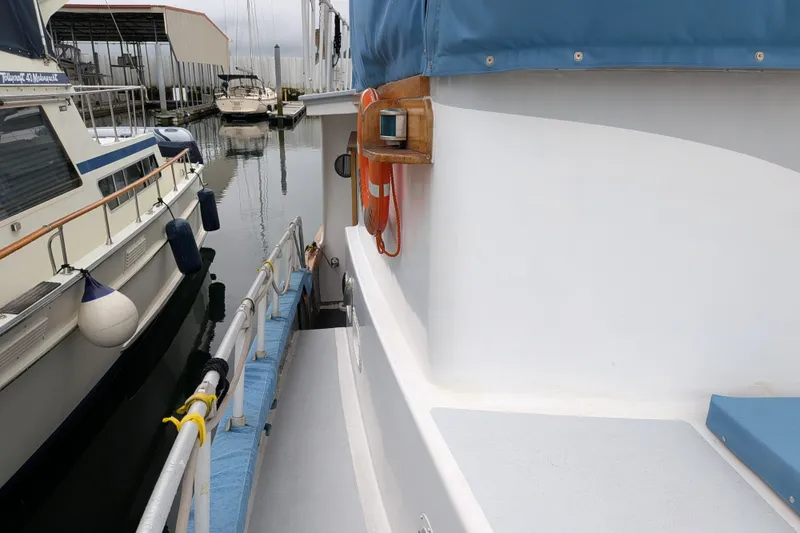 Slide: The Image of 1981 Custom 43 Pilothouse Trawler docked, featuring blue canopy and safety equipment. - 14