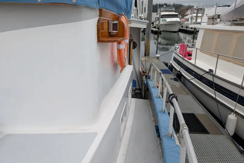 Slide: The Image of 1981 Custom 43 Pilothouse Trawler docked, featuring side deck and marina view. - 13