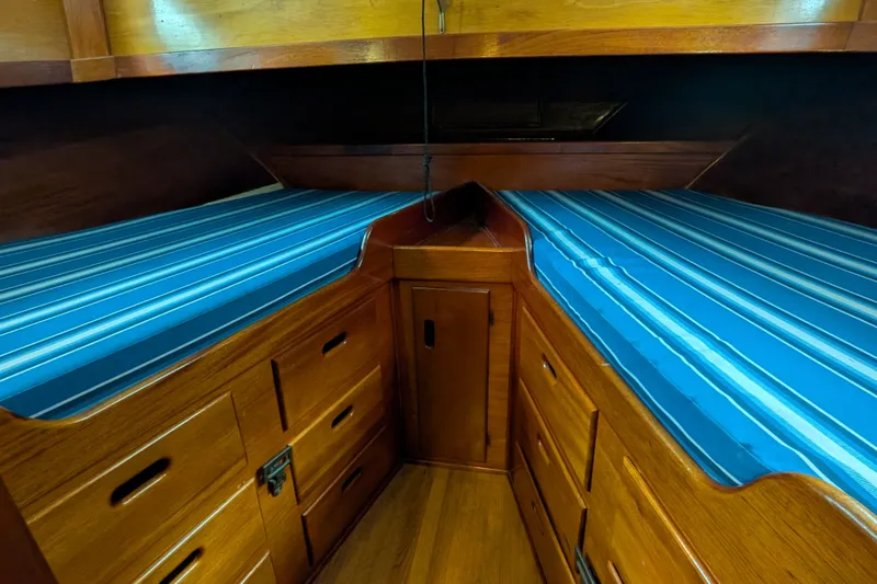Slide: The Image of Interior of 1981 Custom 43 Pilothouse Trawler with blue-striped bedding and wooden cabinetry. - 46