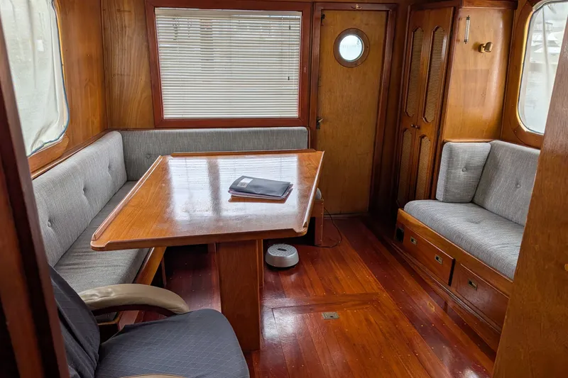 Slide: The Image of Interior of 1981 Custom 43 Pilothouse Trawler with wooden table and gray seating. - 29