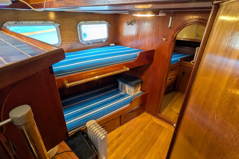Slide: The Image of Interior of 1981 Custom 43 Pilothouse Trawler with wooden bunk beds and blue-striped cushions. - 42