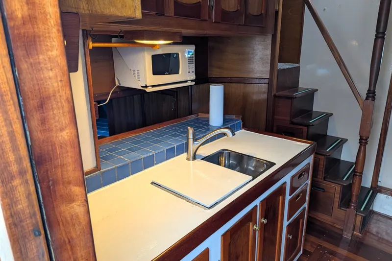 Slide: The Image of 1981 Custom 43 Pilothouse Trawler kitchen with sink, microwave, and wooden cabinetry. - 26