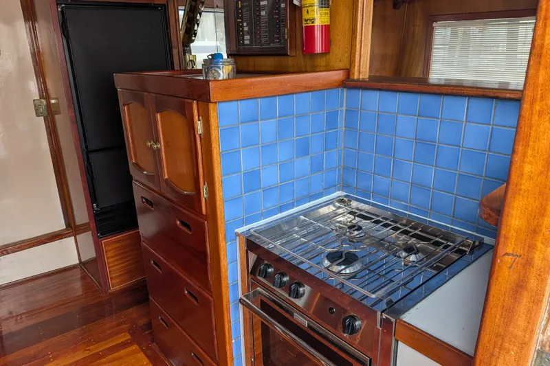Slide: The Image of 1981 Custom 43 Pilothouse Trawler kitchen with blue tile backsplash and wooden cabinetry. - 25
