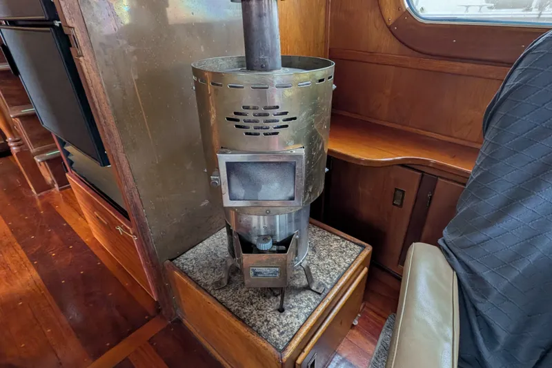 Slide: The Image of Wood stove inside 1981 Custom 43 Pilothouse Trawler, featuring wooden interior and granite base. - 33