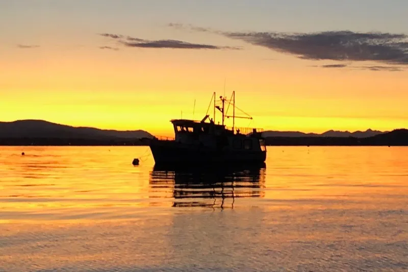 Slide: The Image of 1981 Crown Custom trawler silhouetted against a vibrant sunset over calm waters. - 72