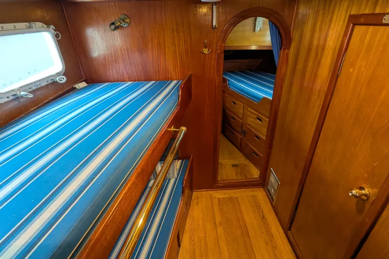 Slide: The Image of Interior of 1981 Custom 43 Pilothouse Trawler with wooden finish and striped bedding. - 43