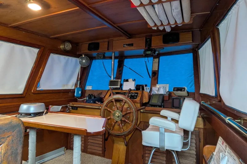 Slide: The Image of 1981 Custom 43 Pilothouse Trawler interior with wooden helm, navigation equipment, and white captain's chair. - 55