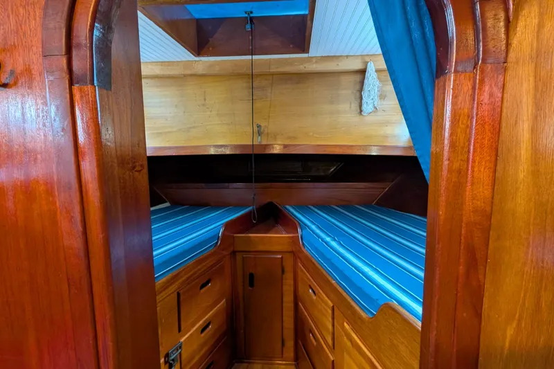 Slide: The Image of Cozy cabin interior of 1981 Custom 43 Pilothouse Trawler with wooden finish and blue-striped bedding. - 45
