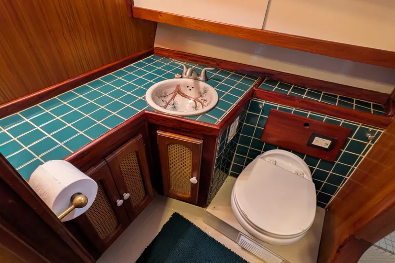 Slide: The Image of 1981 Custom 43 Pilothouse Trawler bathroom with teal tiles, wooden cabinets, and a decorative sink. - 52