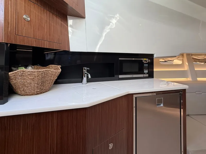 Slide: The Image of The interior view shows a modern kitchen with wood cabinets, a sink, and a microwave. - 49