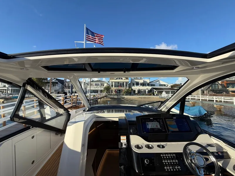 Slide: The Image of The cockpit of the 2022 Sea Ray Sundancer 370 Outboard features modern instruments and an open view of the harbor. - 26