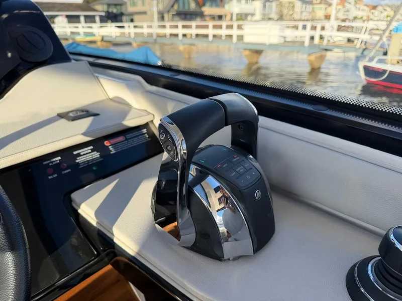 Slide: The Image of Close-up of the throttle control on a 2022 Sea Ray Sundancer 370 Outboard, overlooking a marina. - 39