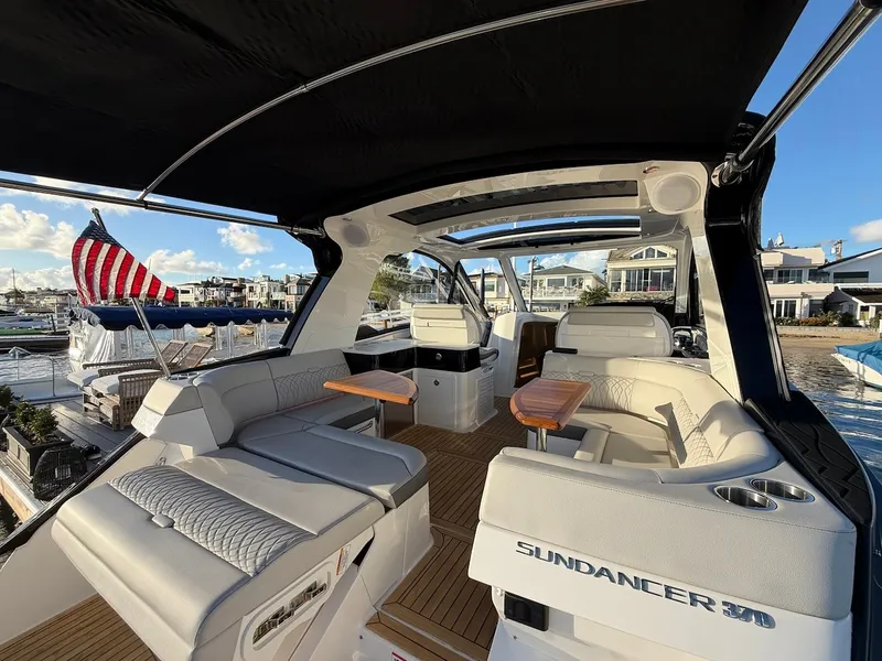 Slide: The Image of The image shows the cockpit of a 2022 Sea Ray Sundancer 370 Outboard with sleek white seating and a wooden table. - 23