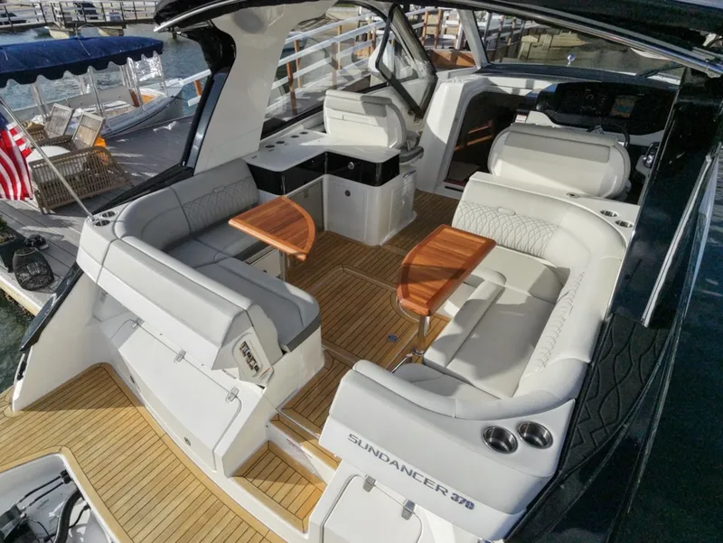 Slide: The Image of The image shows the cockpit of a 2022 Sea Ray Sundancer 370 Outboard with sleek seating and wooden tables. - 14
