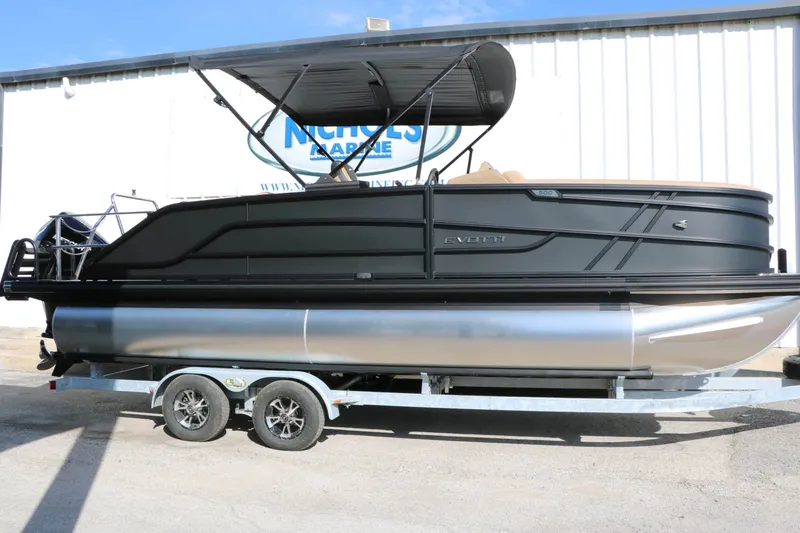 Slide: The Image of A 2027 Evotti 521 CS Tri Toon on a trailer in front of a building. - 2