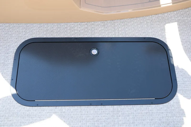 Slide: The Image of A black rectangular hatch on a patterned floor, possibly a compartment cover. - 42