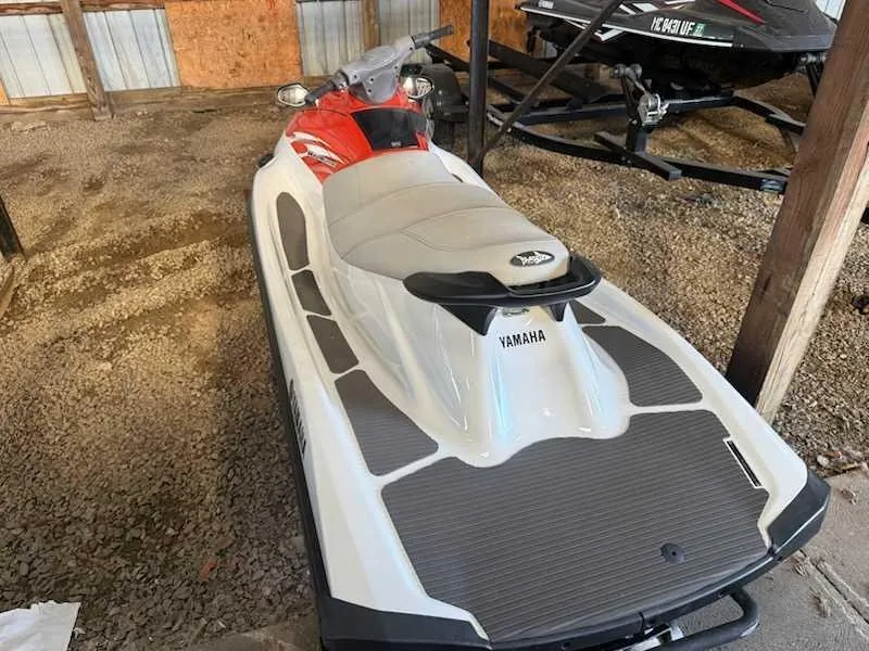 Slide: The Image of A white 2015 Yamaha V1 jet ski is parked in a shed on gravel flooring. - 2