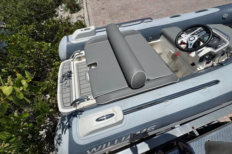 Slide: The Image of 2019 Williams Jet Tenders Sportjet 345, gray seating, steering console, outdoor setting. - 15
