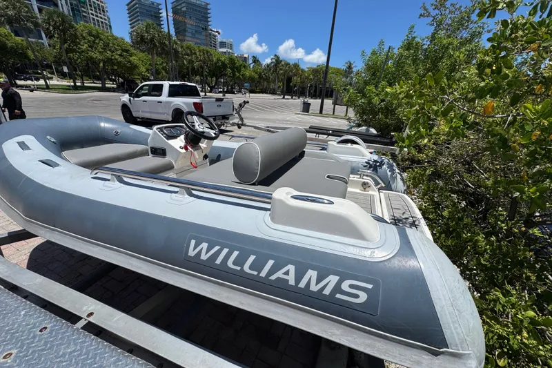 Slide: The Image of 2019 Williams Jet Tenders Sportjet 345 inflatable boat on trailer, parked near trees and buildings. - 11