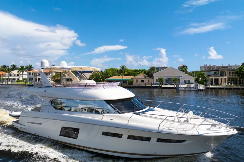 The Image of Luxurious 2013 Prestige 620 yacht cruising on a sunny day near waterfront homes. - 1