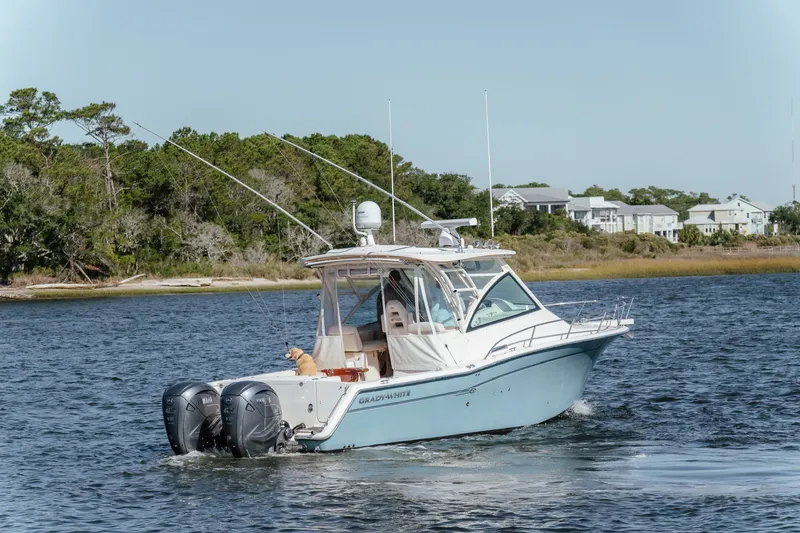 Slide: The Image of 2019 Grady-White Express 330 boat cruising on a scenic waterway with a dog onboard. - 6