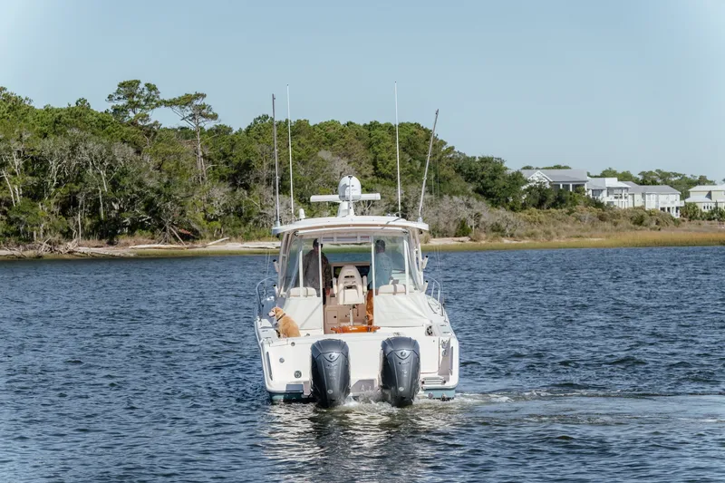 Slide: The Image of 2019 Grady-White Express 330 boat cruising on a serene lake with forested shoreline. - 8