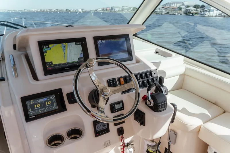 Slide: The Image of 2019 Grady-White Express 330 helm with navigation screens and controls on a sunny day. - 12
