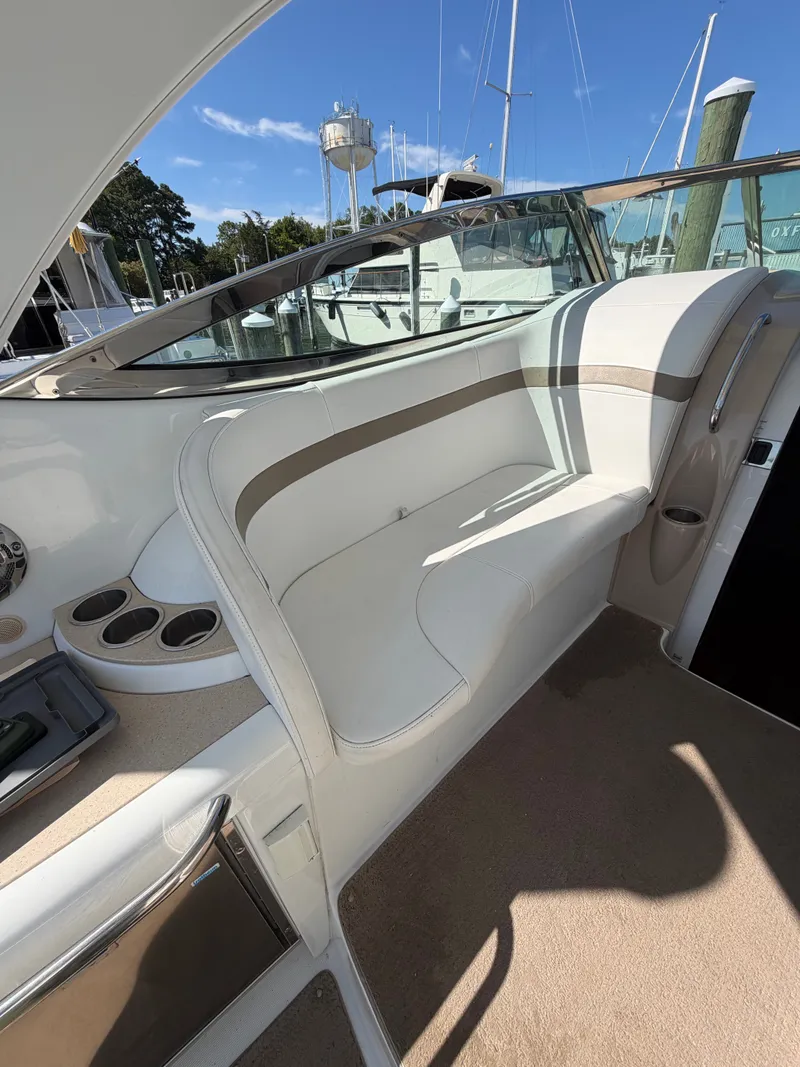 Slide: The Image of Seating area on a boat with white upholstery and cup holders, surrounded by a marina. - 7