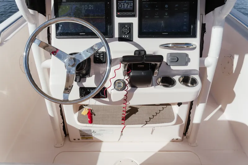 Slide: The Image of 2016 Grady-White Fisherman 257 helm with steering wheel and navigation controls. - 18
