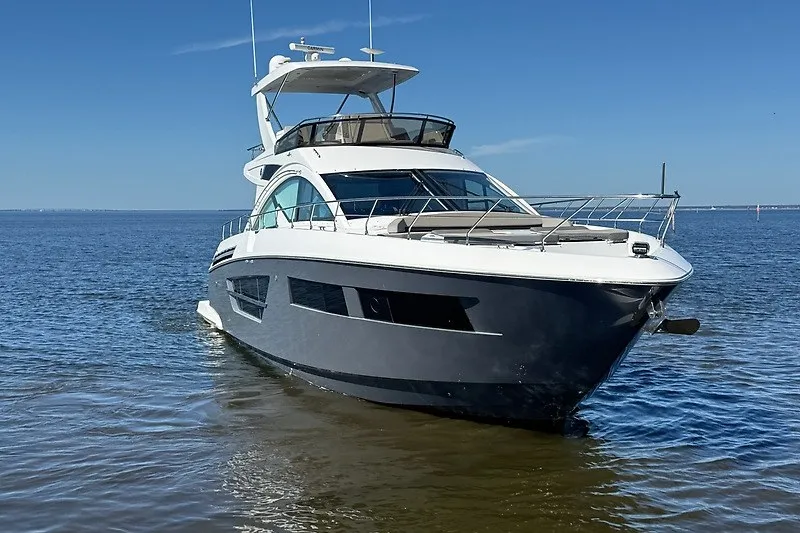 Slide: The Image of 2023 Cruisers Yachts 60 Fly luxury yacht on calm water under clear blue sky. - 2