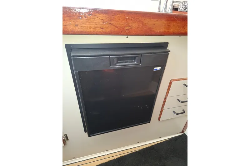 Slide: The Image of 1992 Luhrs Tournament 300 interior with built-in black refrigerator and wooden cabinetry. - 25