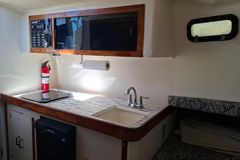 Slide: The Image of 1992 Luhrs Tournament 300 boat interior with kitchenette, sink, and fire extinguisher. - 21