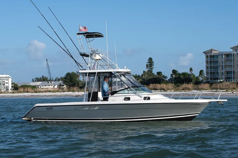 Slide: The Image of 1992 Luhrs Tournament 300 boat cruising near shoreline with buildings in the background. - 6