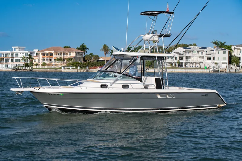 Slide: The Image of 1992 Luhrs Tournament 300 boat cruising near waterfront homes under clear blue skies. - 1