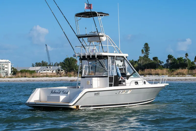 Slide: The Image of 1992 Luhrs Tournament 300 boat cruising near a sandy shoreline under a clear blue sky. - 7