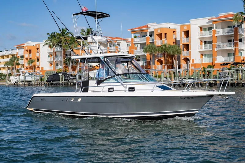 Slide: The Image of 1992 Luhrs Tournament 300 boat cruising near waterfront buildings with palm trees. - 5