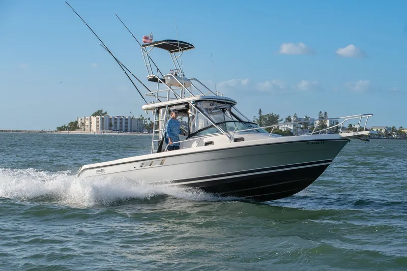 Slide: The Image of 1992 Luhrs Tournament 300 boat cruising on open water, clear sky background. - 11