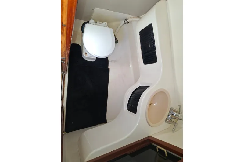 Slide: The Image of 1992 Luhrs Tournament 300 boat bathroom with toilet, sink, and black mat. - 28