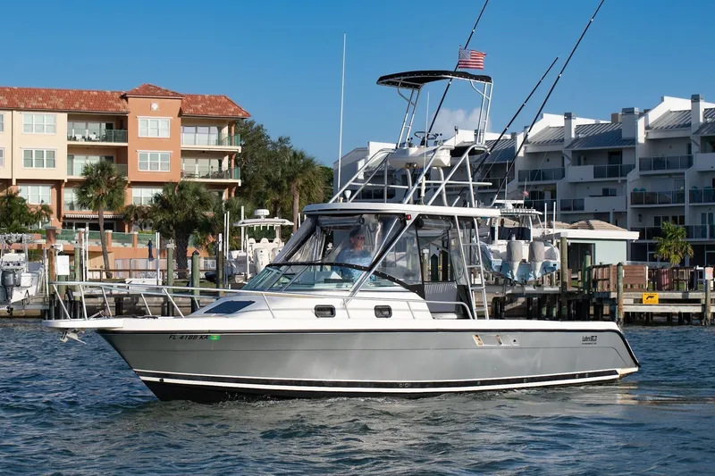 The Image of 1992 Luhrs Tournament 300 boat cruising near waterfront buildings. - 0