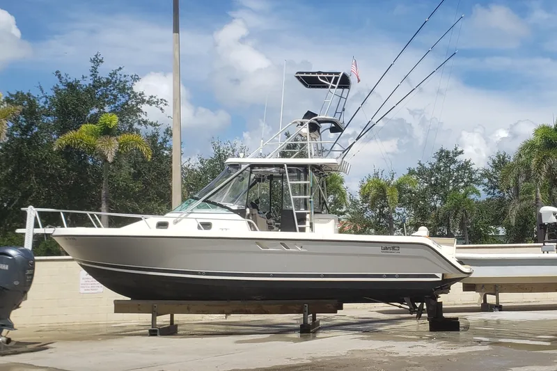 Slide: The Image of 1992 Luhrs Tournament 300 boat on dry dock, surrounded by palm trees and blue sky. - 13